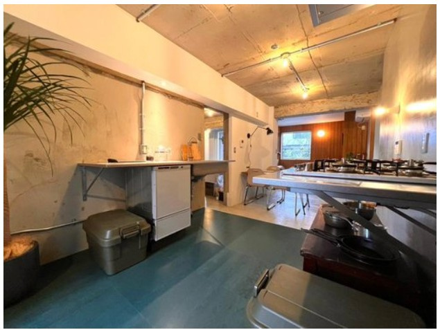 大山崎町円明寺脇山のキッチン|ミニマルなキッチンと、色味のある床、無機質なコンクリートの壁が見事に調和し、細部までデザインされた空間です。