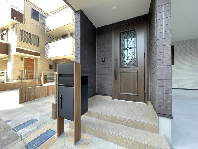 北区志茂3丁目 全3棟 3号棟の玄関|明るいタイルと木目ドアが調和した、温もりあふれるエントランスです(3号棟)