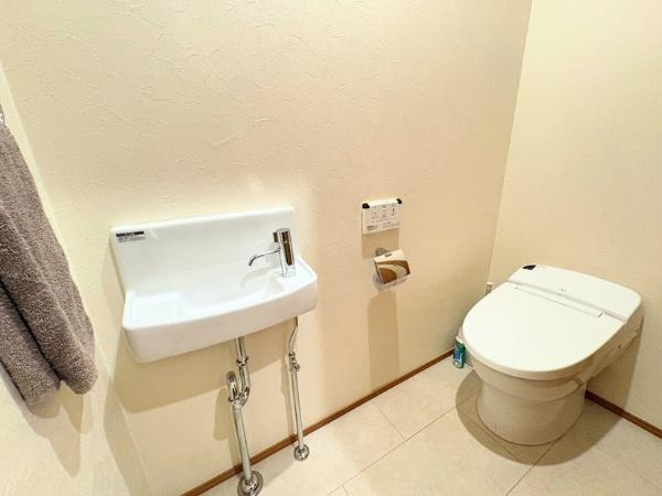 角子原　戸建てのトイレ|落ち着いた色合いの壁と床で清潔感のあるトイレです。手洗い場が備え付けられており便利です。収納スペースも確保されています。空間が広く取られているのが特徴です。シンプルなデザインで使いやすい印象です。