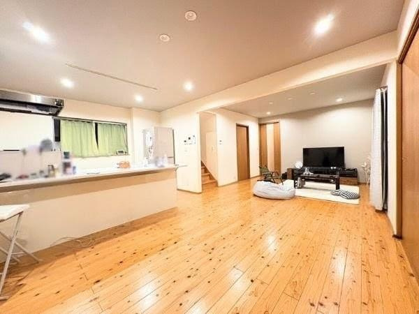 角子原　戸建ての居間・リビング|広々としたリビング空間が特長です。木目調のフローリングが温かい印象を与えます。天井のダウンライトが室内を明るく照らしています。キッチンとリビングが繋がったオープンなレイアウトです。