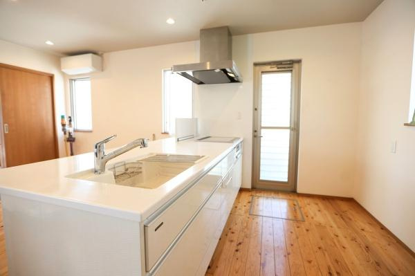 角子原　戸建てのキッチン|シンプルで使いやすいデザインのキッチンです。広々としたカウンターが特徴的です。木目調のフローリングが温かみを演出しています。収納スペースも充実しています。勝手口があり通気や動線にも配慮されています。