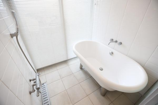 青葉台　戸建ての浴室|独立型のバスタブが設置されておりゆったりとした印象のバス空間です。ホワイトを基調としたタイルとバスタブが調和しています。大きな窓からの採光で明るい雰囲気が広がっています。