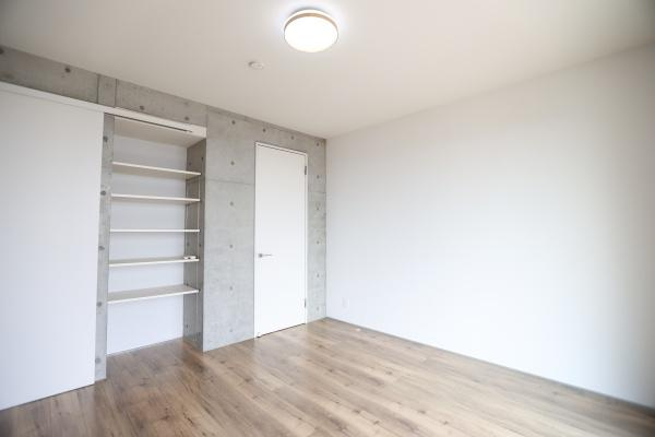 青葉台　戸建ての洋室|ナチュラルな色合いのフローリングが落ち着いた雰囲気を演出します。コンクリート調の壁がアクセントとなりスタイリッシュな空間です。壁面には便利なオープン棚が設けられています。