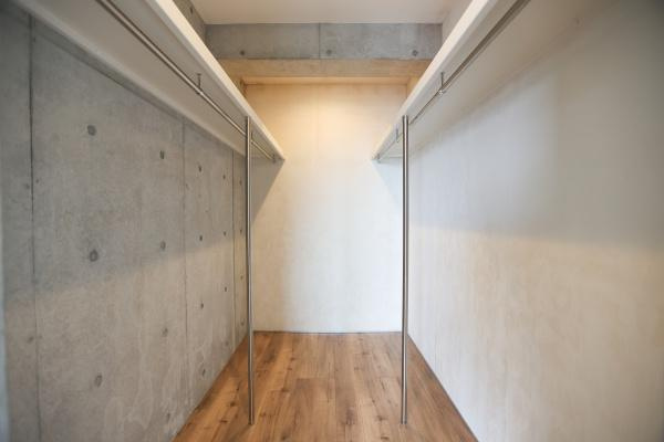青葉台　戸建ての収納|コンクリート打ちっぱなしのデザインが印象的な収納スペースです。両側にハンガーパイプが設置されており効率的に活用できそうです。奥行きがあるため収納力にゆとりがあります。