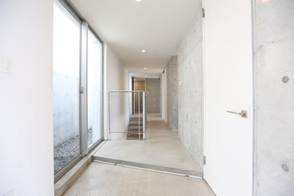 青葉台　戸建ての内装|白を基調とした明るい廊下はガラス窓から自然光が多く入り開放感があります。コンクリート打ちっぱなしの壁が都会的な印象を与えます。シンプルなデザインが空間を広く見せます。