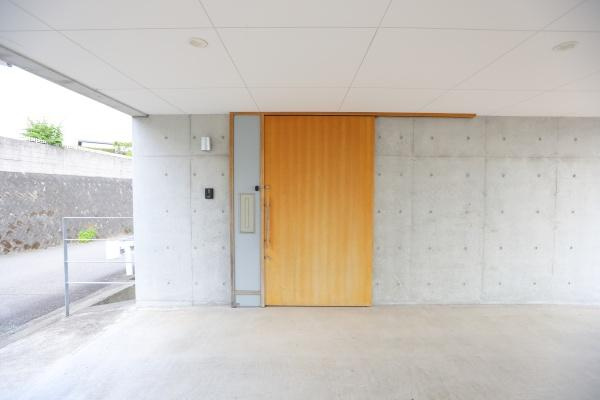 青葉台　戸建ての玄関|無機質なコンクリートと木目のコントラストが外観に個性を与えています。シンプルで洗練された玄関デザインです。引き戸仕様が機能的で使いやすい印象を与えています。