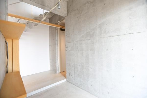 青葉台　戸建ての玄関|コンクリート打ちっぱなしの壁が印象的な玄関です。シンプルで洗練された雰囲気が広がります。明るい光が差し込み空間をすっきりと見せています。収納棚が設置されており使い勝手にも配慮されています。