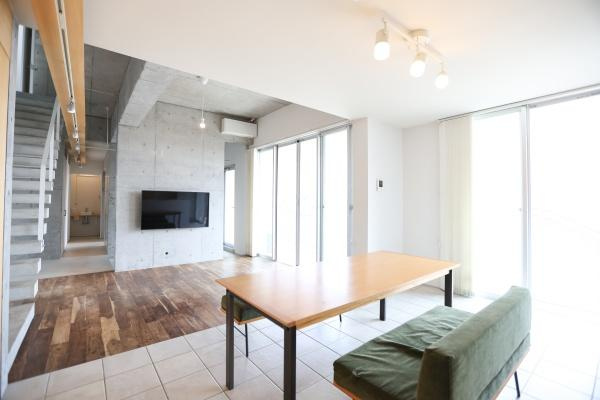 青葉台　戸建ての居間・リビング|リビングは大きな窓から光が差し込み明るい空間です。天井や壁のコンクリートが洗練された印象を与えます。床材の切り替えがアクセントとなっています。スタイリッシュな照明も特徴です。