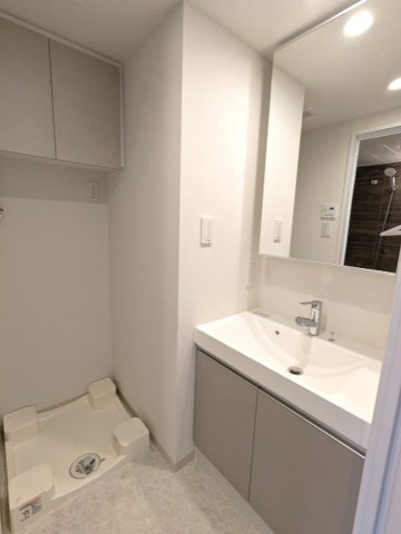 PROUD FLAT日本橋馬喰町の洗面所|トイレと独立した洗面室、ハンドシャワー付洗面台、洗濯機置場は排水口のお手入れし易く手前中央に配置し、足高の防水パンです