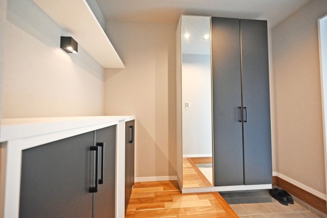 ハッピータウン尼崎田能4丁目の玄関|天井まで届く玄関収納は姿見鏡付き。玄関を彩るインテリアも飾れる収納もあり、玄関回りとスッキリと片付けられます。