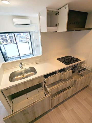 エスレジデンス浅草clarityのキッチン|グリル付ガス3口システムカウンターキッチン、奥の物も取り出しやすいスライド収納、瀟洒でお手入れ楽なガラストップコンロです、広々のシンクです