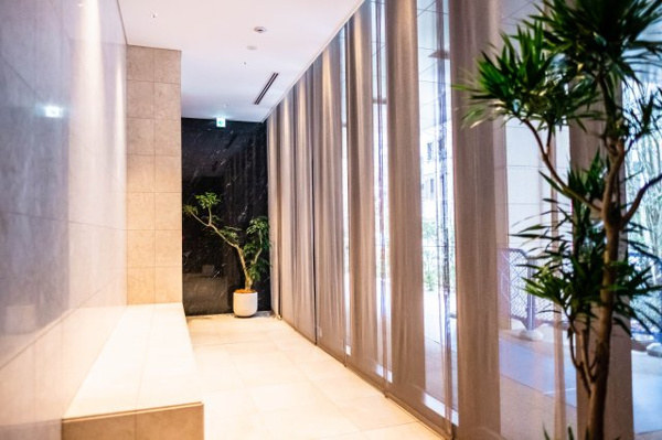 【エントランス】 | 【エントランス横通路】一面のガラスウォール越しに、エントランス周辺の潤い豊かな植栽が見える憩いの場。