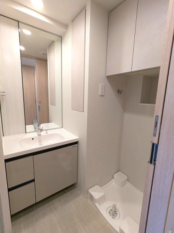 LEFOND PROGRES上野御徒町の洗面所|トイレと独立した洗面室、ハンドシャワー付独立洗面台、タオルフックにスマホストレージ付です、洗濯機置場上段収納の下にハンガー収納パイプ付、排水口のお手入れしやすい様に中央手前に配置し、足高の防水パンです