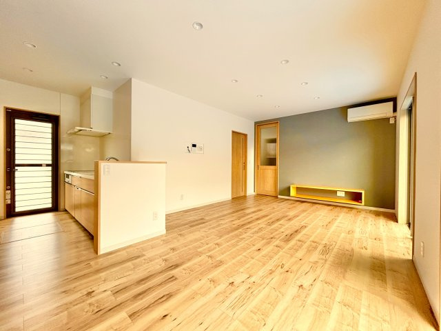 高知市竹島町　中古住宅の居間・リビング|温かみのある木目フロアに、グレーのアクセント壁が映える上質なLDK。TVボードも造作されており、暮らしやすさとデザイン性を兼ね備えた空間です。