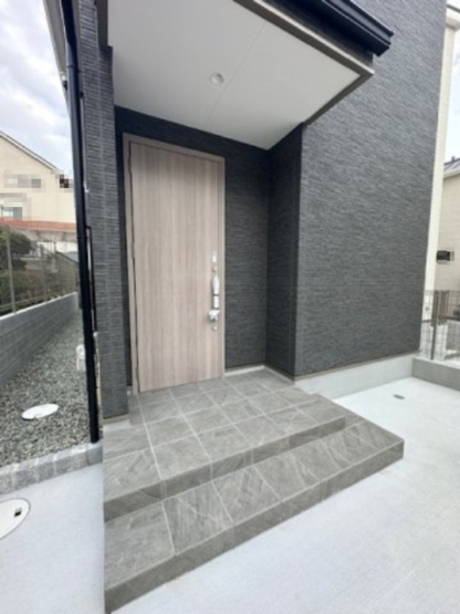 【玄関】 | プルメリア永楽荘3丁目Ⅱ　2号地 | 屋根付きのポーチで雨天時も鍵の開閉や荷下ろしもラクラク！陽当り・周辺環境も合わせて、ぜひ現地をご覧ください。