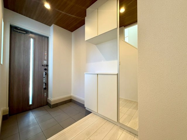 高知市高須3期2棟 2号棟の玄関|木目天井と扉の統一感が美しい玄関。鏡付きの収納が空間を広く見せ、明るく上品な印象に仕上がっています