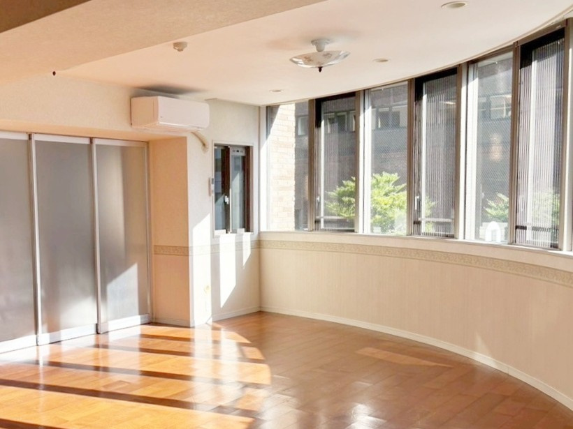 エクセルシティ三宮イメージファクトリーの居間・リビング|カーブを描く窓辺が印象的で、空間のラインに合わせたレイアウトを楽しめます