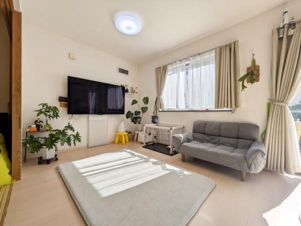 坂ノ市中央　中古の居間・リビング|リビングには大きな窓があり自然光が差し込み明るい空間です。テレビが壁に設置されレイアウトがすっきりしています。