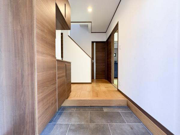 津守　中古の玄関|グレーのおしゃれな土間と木目調の収納が印象的な玄関です。段差があり住宅の内部と外部をしっかり区切る造りです。