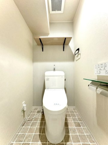 ビッグヴァン二俣川ホームズのトイレ|デザインクロスと木調棚が調和するナチュラルモダンなトイレ空間。温水洗浄便座付きで機能面も充実しています。