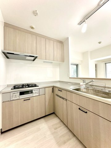 ビッグヴァン二俣川ホームズのキッチン|木目調のL字型システムキッチン。調理スペースが広く、食洗機や3口コンロを備えた機能的な設計が魅力です。