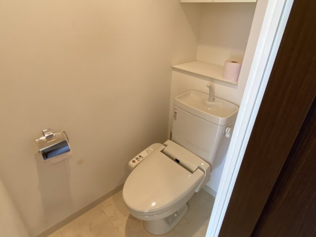 アルファステイツ神拝のトイレ|清潔感あふれる温水洗浄便座を完備したトイレ。手洗い場や収納棚も使いやすく配置され、限られた空間でも快適に過ごせるよう配慮されています。落ち着いた内装が安らぎを与え、日々の清潔を保つ最新の仕様。