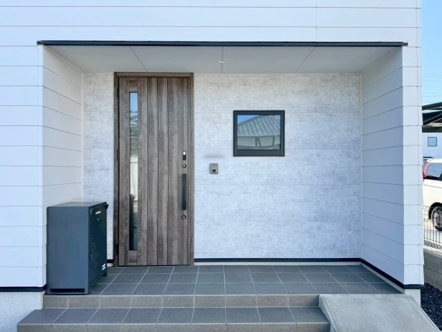 守山市大門町　中古戸建てのエントランス|真っ白の外壁にアクセントとなる木目の扉など、デザイン性の高いポーチ部分。