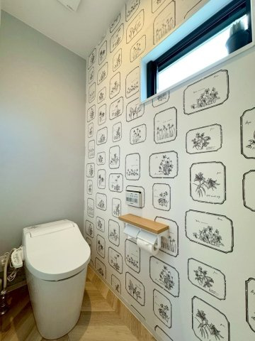 守山市大門町　中古戸建てのトイレ|アクセントクロスとヘリンボーン風の床がマッチしていて、お洒落な雰囲気の1Fトイレ。