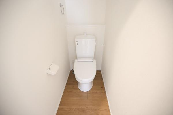 横尾東町2丁目2期1号棟のトイレ|シンプルなデザインのトイレです。清潔感のある白を基調とした空間が特徴です。床はナチュラルな木目調で落ち着いた印象です。使いやすい配置がされています。ペーパーホルダーも設置されています。