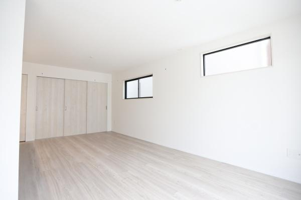 横尾東町2丁目2期2号棟の洋室|明るい色合いのフローリングが特徴的な洋室です。二つの窓から光が差し込み開放感があります。クローゼットも設置されており収納スペースも確保されています。壁や床の配色が統一されておりすっきりとした印象です。