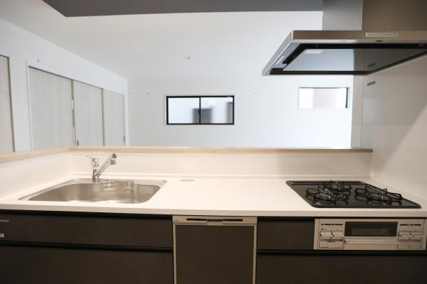 横尾東町2丁目2期2号棟のキッチン|キッチン全体がすっきりとしたデザインで使いやすさが感じられます。広々としたワークトップで作業がはかどります。ガスコンロとシンクの配置も使いやすい印象です。手元が広く収納スペースも確保されています。