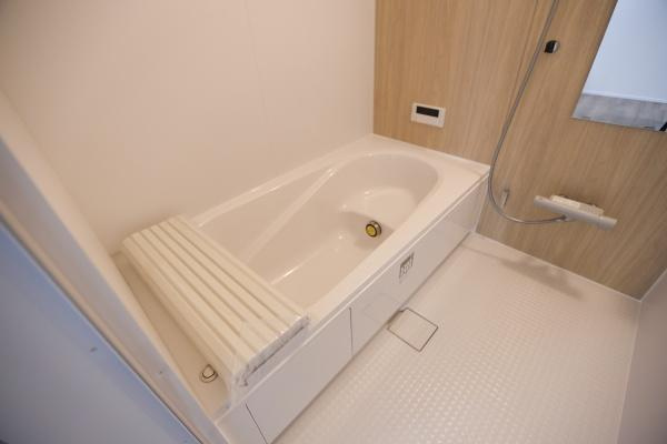 横尾東町2丁目2期3号棟の浴室|シンプルなデザインのバスルームです。浴槽がゆったりしており手入れしやすい床材が採用されています。木目調の壁パネルが温かみを感じさせます。浴槽カバーがついているので使い勝手も良好です。