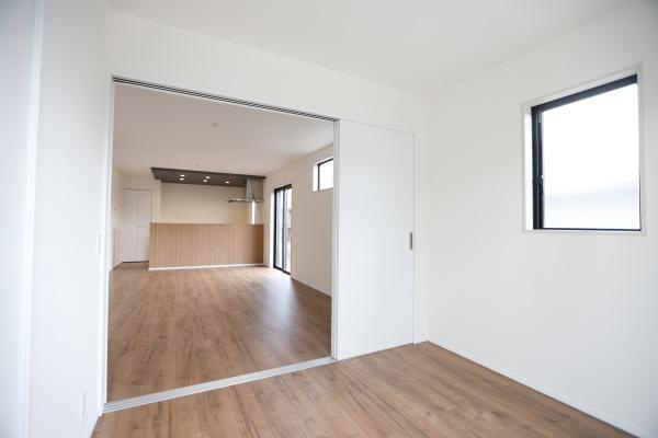 横尾東町2丁目2期3号棟の洋室|ホワイトを基調とした内装にナチュラルなフローリングが調和しています。洋室とリビングの間仕切りが広がりを演出します。窓からはやわらかな光が差し込む空間です。