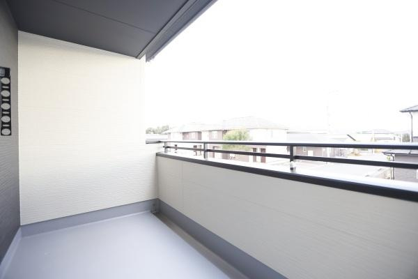 横尾東町2丁目2期3号棟のバルコニー|開放感のある広々としたバルコニーです。しっかりとした手すりで安心感があります。屋根付きなので天候の影響を受けにくい造りです。外の景色も楽しめます。清潔感のある空間が広がっています。