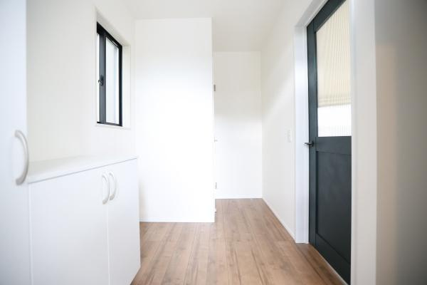 横尾東町2丁目2期3号棟の玄関|明るい玄関スペースが広がり清潔感のあるホワイトの収納が設置されています。ナチュラルな木目調の床が温かみを感じさせます。窓からの採光で玄関全体がすっきりとした印象です。