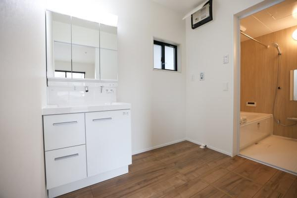 横尾東町2丁目2期3号棟の洋室|明るい色合いの床材が特徴の洋室です。シンプルな洗面台が備わり清潔感のある空間が広がっています。窓も設置されているので自然光が差し込みやすいです。浴室との動線も良好です。
