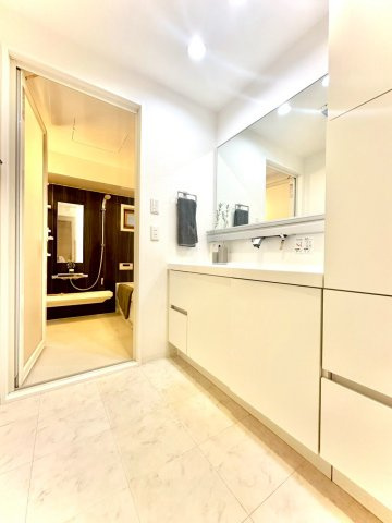 ピュアハイツ南万騎が原の独立洗面台|大理石調の床が上品な洗面室。ワイドミラーを備えた洗面台と、奥にはゆとりのバスルームが続きます。