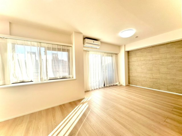 東急ドエルアルス大倉山東の居間・リビング|大きな窓からたっぷり光が差し込む明るいリビング。アクセント壁が空間を引き締め、上質なインテリアが映える雰囲気です。