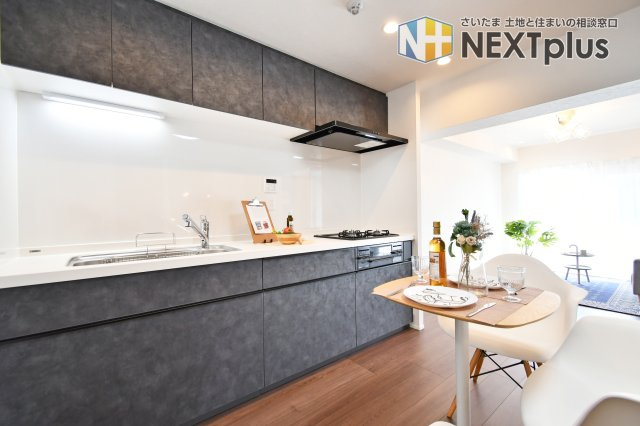 扶桑ハイツ春日部のキッチン|黒基調の吊戸棚付きシステムキッチンです。上にも下にもたくさん収納出来ますので、別途で食器棚がなくてもたくさん収納する事ができます！ライトもありますので、お料理中の手元もしっかり照らしてくれます。