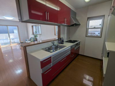 【キッチン】 | 緑町２丁目　中古戸建 | 赤色がおしゃれなシステムキッチンです。