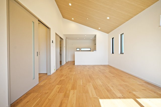 グランエスポワール中野北【全19区画】の居間・リビング|高さと開放感のある勾配天井のリビング。天井の配色を変えることでより空間に広がりができています。光をさえぎる建物の無い、バルコニーからの光が差し込む明るい空間です。