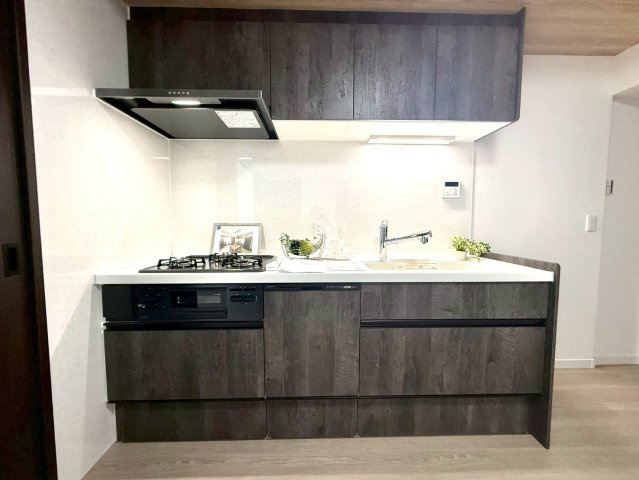 セザールたまプラーザのキッチン|重厚感のあるダークウッド調のシステムキッチンを採用。広いワークトップと収納力で、毎日の家事を快適にサポートします。