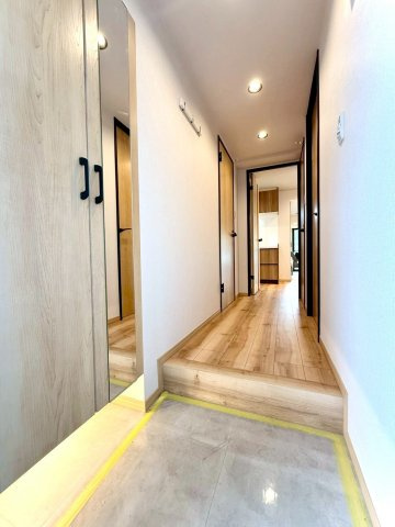 扶桑ハイツ南太田の玄関|温かな木目が迎える玄関ホール。
全身鏡付きのシューズボックスでお出かけ前の身だしなみチェックも安心です。上質な照明が廊下を上品に照らします。