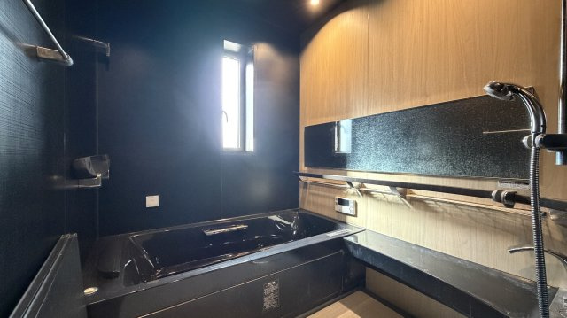 紫山5丁目　中古土建の浴室|シックな色合いの広々としたバスルーム。ダークな色合いの室内に外光がまぶしく差し込みます。