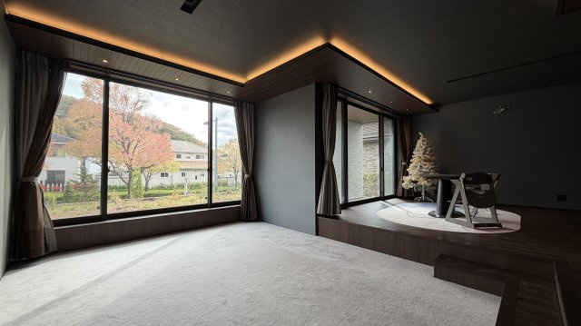 紫山5丁目　中古土建の居間・リビング|窓の向こうは木々や植栽が四季折々の彩りを添える。春夏秋冬の季節の移ろいの彩のすべてが大パノラマとなって、日々の暮らしに豊かな詩情をもたらします。