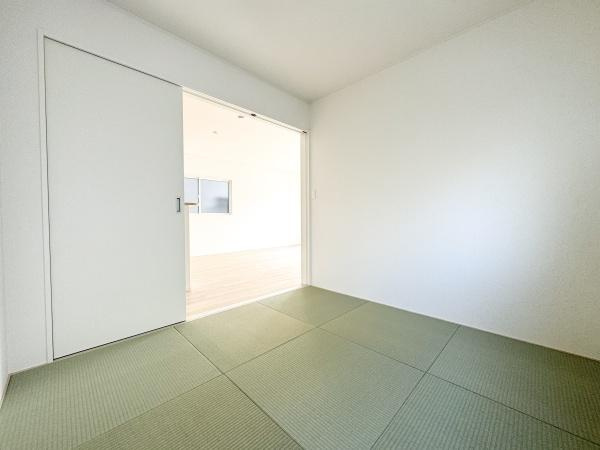 徳島第7-1号棟の和室|シンプルなデザインで落ち着いた雰囲気の和室です。広々とした空間が広がっており引き戸で他空間と繋がっています。自然光が差し込む明るい室内も魅力的です。畳がきれいに敷き詰められており清潔感があります。