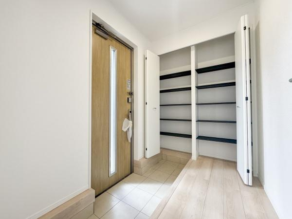 徳島第7-1号棟の玄関|玄関スペースが広々としており快適に出入りできます。明るい光が差し込むドアデザインです。収納棚が備え付けられているので整理整頓しやすい玄関です。清潔感のある内装が魅力的です。