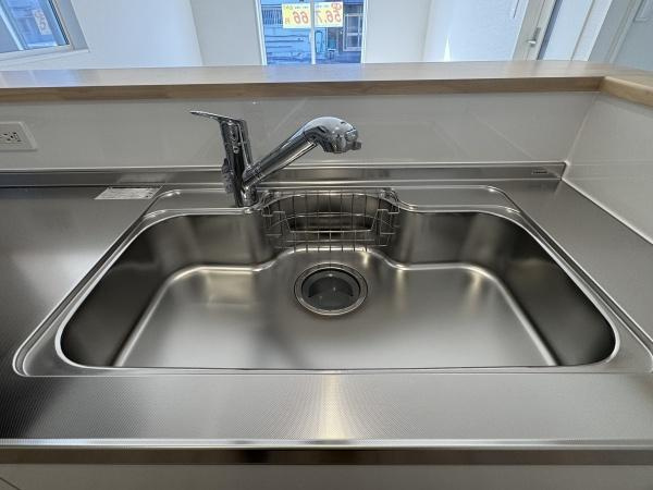 徳島第7-1号棟のキッチン|広々としたシンクが特徴のキッチンです。手入れがしやすいステンレス素材で清潔感があります。水栓や作業スペースも充実しています。使い勝手の良いデザインが魅力です。明るい空間で作業がしやすいキッチンです。