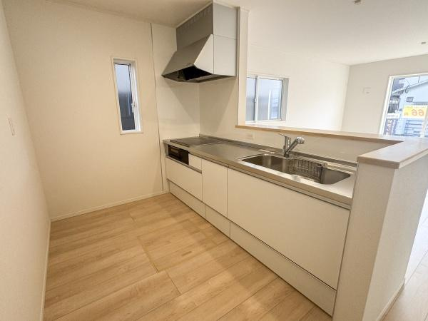 徳島第7-1号棟のキッチン|シンプルで洗練されたデザインのキッチンです。作業スペースが広く日々の調理も快適に行えます。勝手口につながる小窓があり通気性にも配慮されています。シンクや収納も充実しており使いやすさが感じられます。