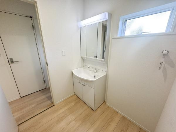 徳島第7-1号棟の独立洗面台|明るい室内に設置された洗面台が特徴的です。収納スペースもしっかり確保されており整理整頓がしやすい仕様です。窓が配置されているため自然な採光が期待できます。